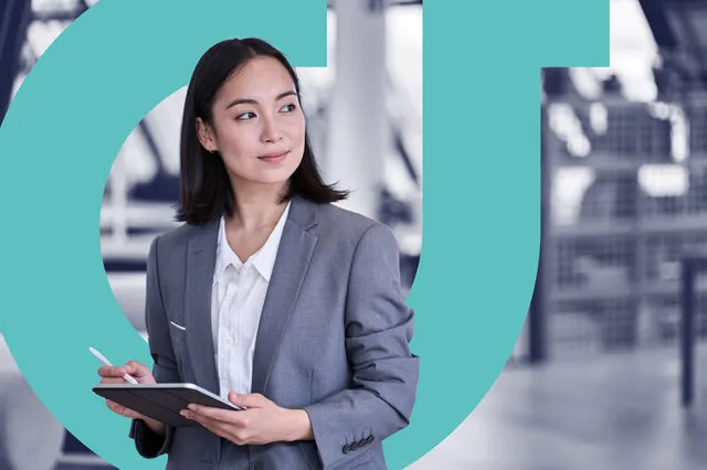The image shows a woman dressed in a grey blazer and white shirt, holding a tablet and pen. She is stood in a modern office environment, and the logo for Assured Thought - a light blue 'a' is layered behind.